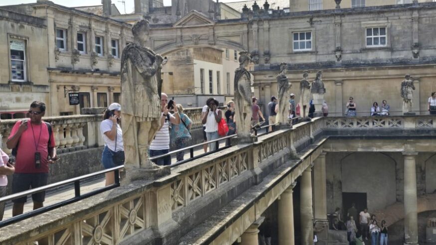 Roman sculptures surround the main pool in The Roman Baths