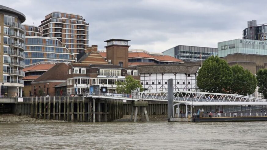 A view of Shakespeare's Theator (round white building thith thatch roof).